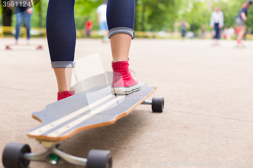 Image of Teenage girl practicing riding long board.