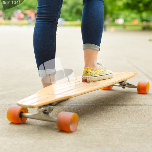 Image of Teenage girl practicing riding long board.