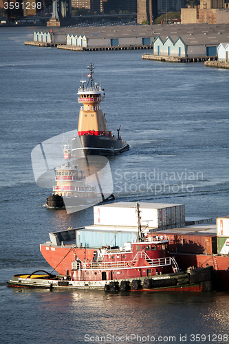 Image of Tugboats and cargo ship in East River