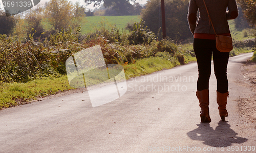 Image of Young woman walks up a country lane alone