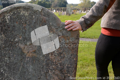 Image of Woman\'s hand resting on a gravestone