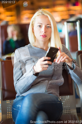 Image of Female traveler using cell phone while waiting.