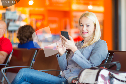 Image of Female traveler using cell phone while waiting.