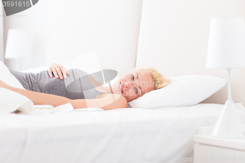 Image of Young woman waking up with smile on face.