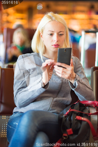 Image of Female traveler using cell phone while waiting.