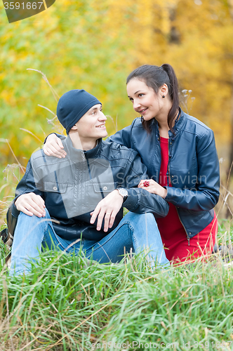 Image of Young romantic couple sits on plaid. Autumn picnic