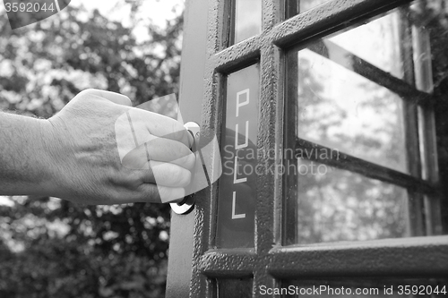 Image of Man\'s hand pulls open door of phone box