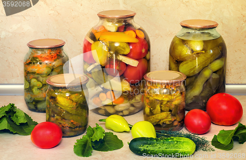 Image of Canned cucumbers with spices in glass jars.