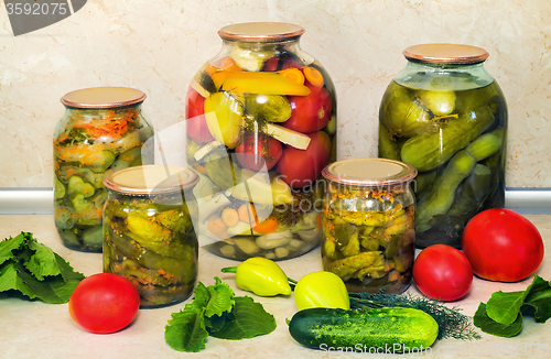 Image of Canned cucumbers with spices in glass jars.