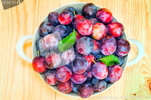 Image of Large plum in a ceramic vase on the table.