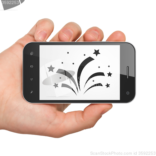 Image of Holiday concept: Hand Holding Smartphone with Fireworks on display