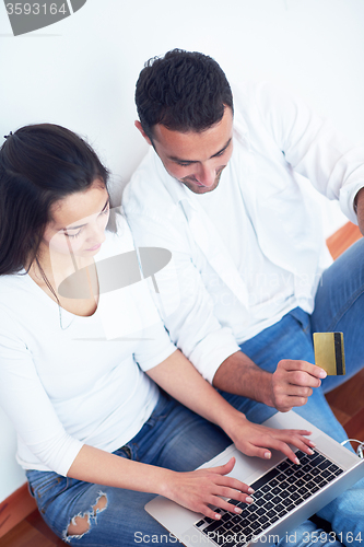 Image of relaxed young couple working on laptop computer at home