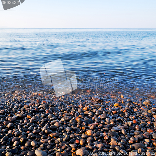 Image of stone in the coastline sunrise and light ocean white sky