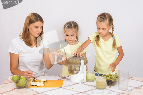 Image of Mom teaches children to squeeze the juice in a juicer