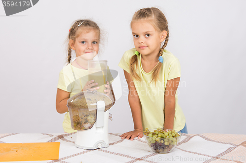 Image of Girls holding a large glass of juice squeezed in a juicer