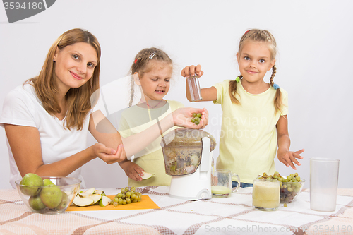 Image of She and her two daughters squeezed juice in a juicer