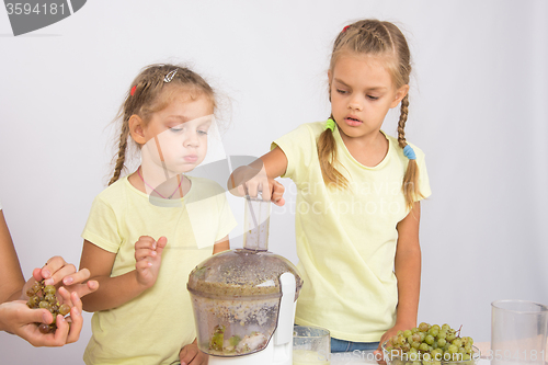 Image of The girl ate a slice of pear is another girl squeezes out juice