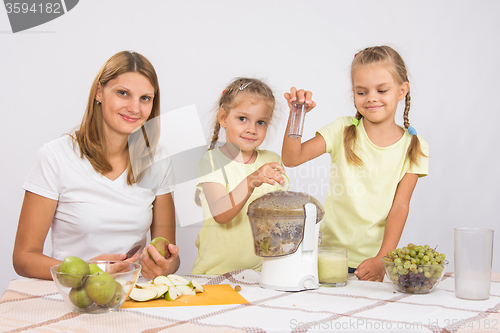 Image of Happy family prepares freshly squeezed juice in a juicer