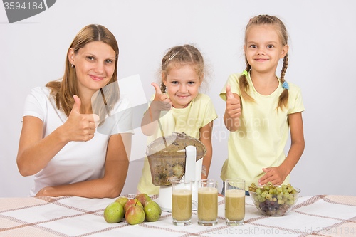 Image of Mother and two daughters show a thumbs up by preparing freshly squeezed juice