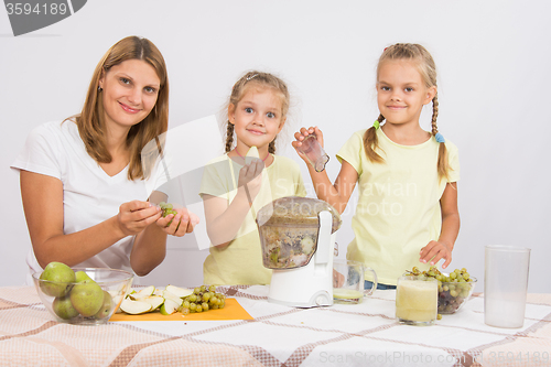 Image of Mother and daughter squeezing juice from pears and grapes