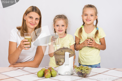 Image of Mother and two daughters with glasses of freshly made juice from the pears and grapes