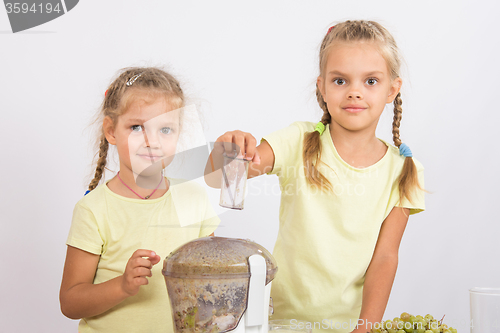 Image of Two girls looking to frame squeezing fruit juice in a juicer