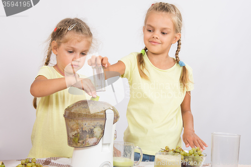Image of Two girls squeezed juice in a juicer