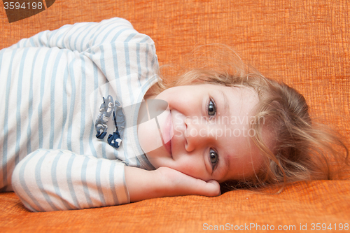 Image of The three-year cheerful girl lying on the sofa