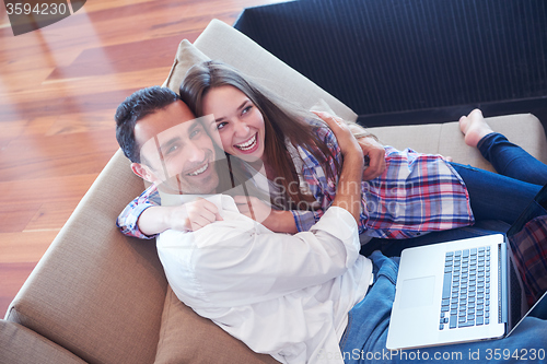 Image of relaxed young couple working on laptop computer at home