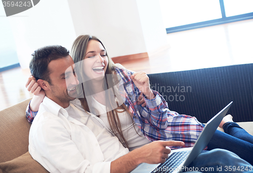 Image of relaxed young couple working on laptop computer at home