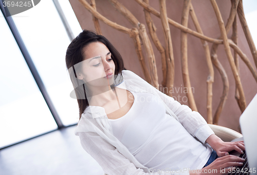 Image of relaxed young woman at home working on laptop computer