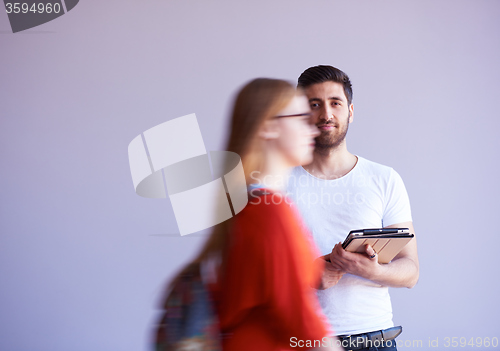 Image of student working on tablet, people group passing by