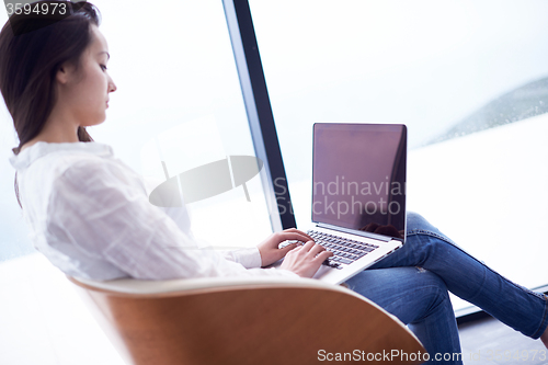 Image of relaxed young woman at home working on laptop computer