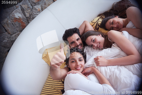 Image of handsome man in bed with three beautiful woman