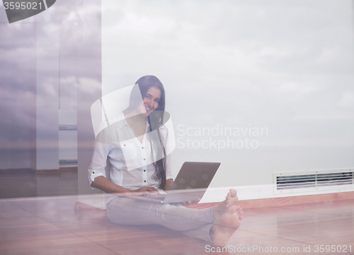 Image of relaxed young woman at home working on laptop computer