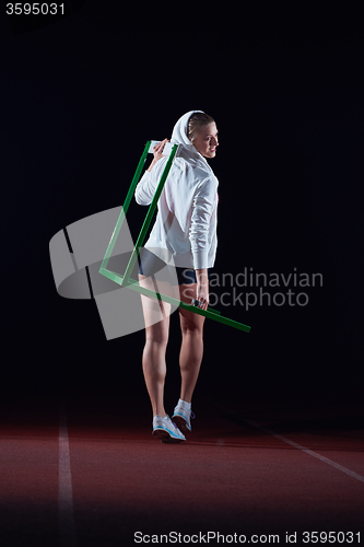 Image of woman athlete jumping over a hurdles