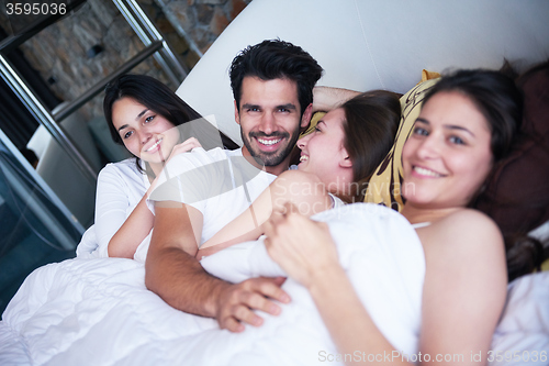 Image of handsome man in bed with three beautiful woman