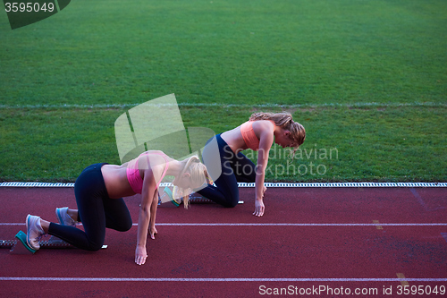 Image of woman group  running on athletics race track from start