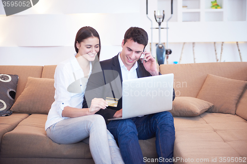 Image of relaxed young couple working on laptop computer at home