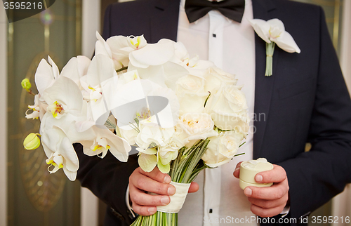 Image of groom with rings and bouquet