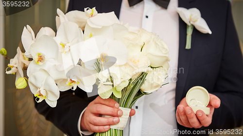 Image of groom with rings and bouquet