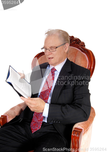 Image of Mature man in suit reading book.