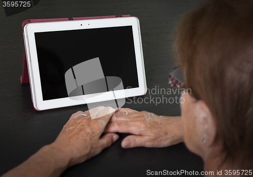 Image of Senior lady relaxing and reading the screen of her tablet