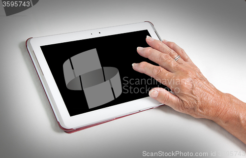 Image of Hand of senior lady relaxing and reading the screen of her table