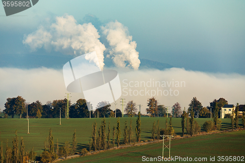 Image of smoking chimneys in from factory hidden in mist