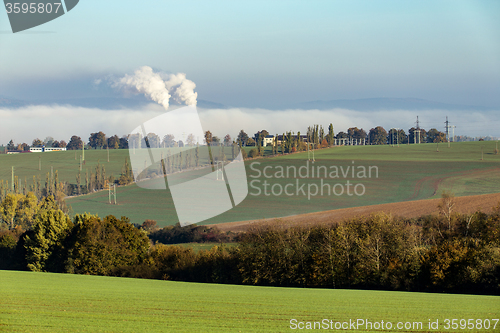 Image of smoking chimneys in from factory hidden in mist