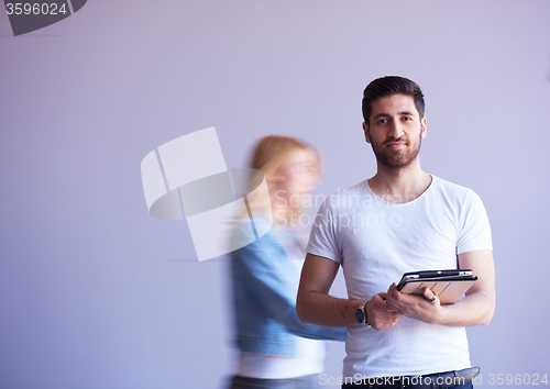 Image of student working on tablet, people group passing by