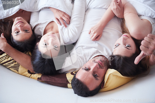 Image of handsome man in bed with three beautiful woman