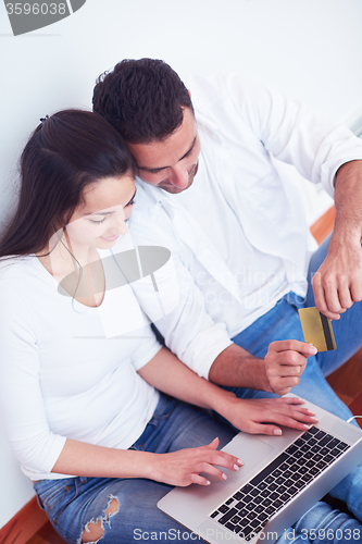 Image of relaxed young couple working on laptop computer at home