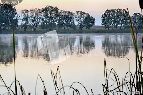 Image of A fisherman in a boat sailing in the morning mist